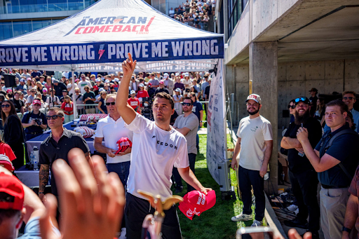 Charlie Kirk (center) was fatally shot at an event at Utah Valley University. At the time of the attack, he was sitting under the pictured white “Prove Me Wrong” tent. (Photo courtesy of PBS News)